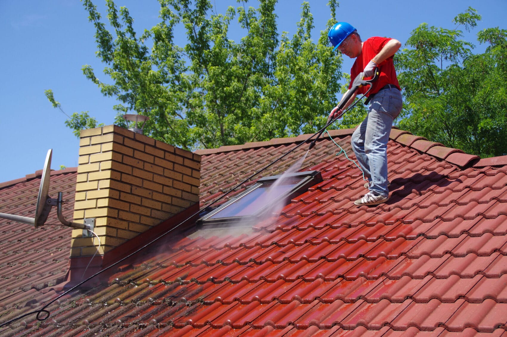 Man on cleaning roof with a pressure washer